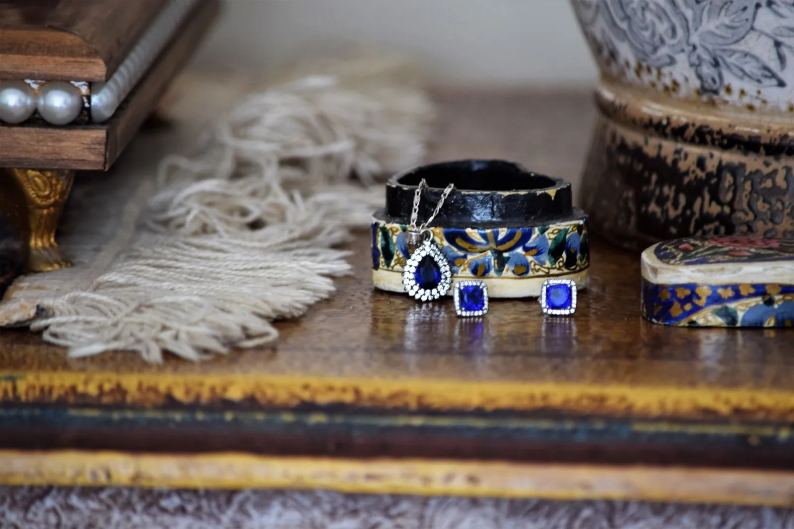 Close-up of elegant jewelry including earrings and pendant on a rustic table setting.